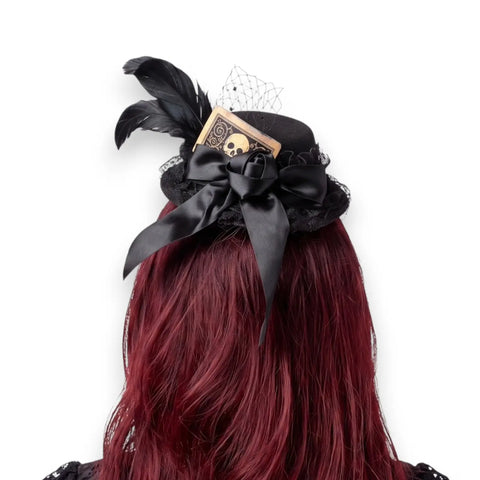 Black mini top hat fascinator with rooster feathers, lace, fishnet veil, satin bow and skull card detail