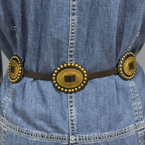 Black faux leather thin strap concho belt with five etched floral gold oval conchos and single pin buckle closure, adjustable waist 25 to 33 inches