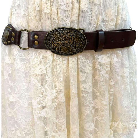 Western floral buckle medallion wide belt in brown or black vegan leather with antique gold studs rivets and O-rings, adjustable buckle closure, 1 3/8 inch strap width