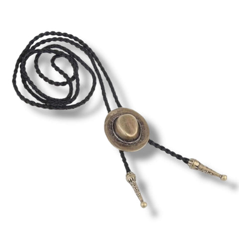 Western brass cowboy hat bolo tie with antique brass hat pendant, black braided leather rope, and silver-tipped ends styled for boho and western fashion.