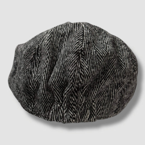 Gray tweed herringbone newsboy cap with short stiff brim and button top, styled as a vintage men’s flat cap.