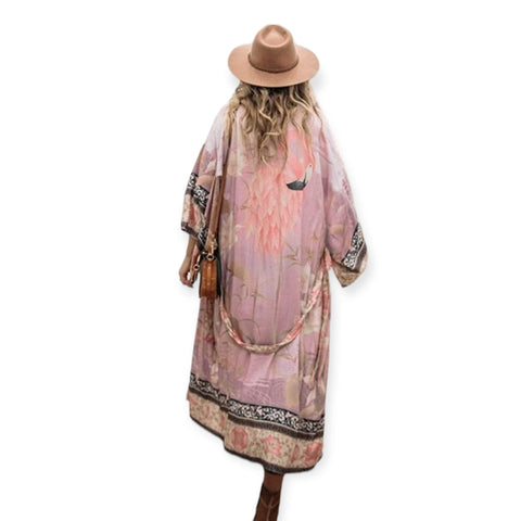 woman wearing wide brim hat with pink flamingo print kimono beach cover up with floral design and sash