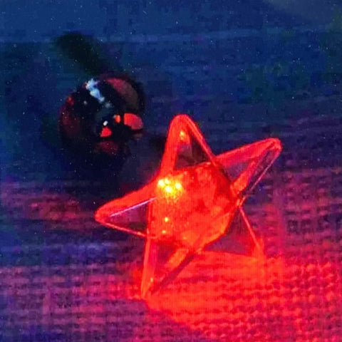 Red LED light up star stud earrings glowing in solid and flashing modes, festival-ready unisex jewelry.