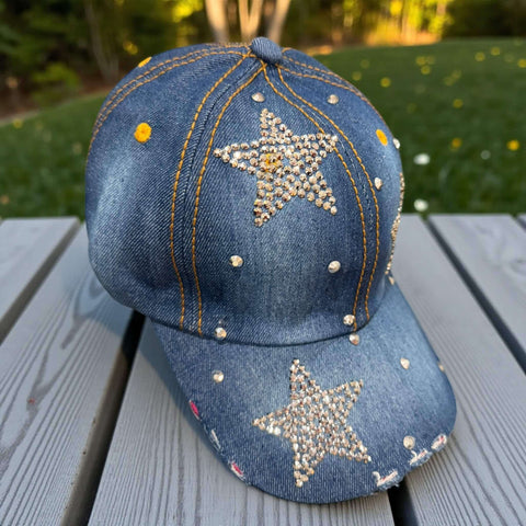Dark blue denim baseball cap with rhinestone star and silver stud detailing on front and brim, curved stiff brim, adjustable back strap, head size 21 to 24 inches