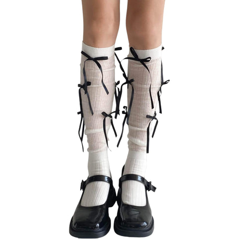 White knee high socks with bold black satin bow ribbons, balletcore legwear for Y2K and festival fashion.