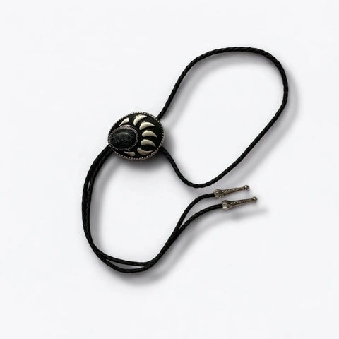 Two bear paw bolo ties with black braided leather cords: silver-tone faux turquoise bear claw slider and black stone bear paw pendant with antique metal tips.