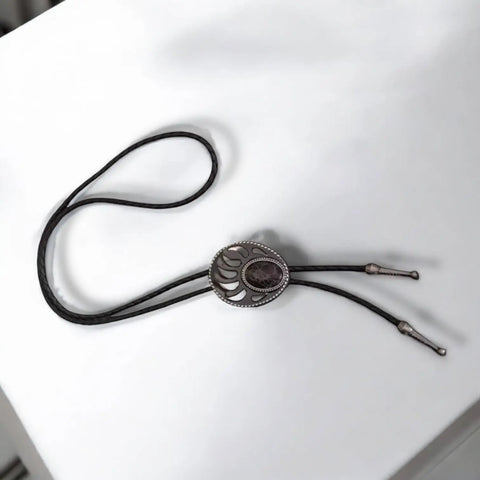 Two bear paw bolo ties with black braided leather cords: silver-tone faux turquoise bear claw slider and black stone bear paw pendant with antique metal tips.