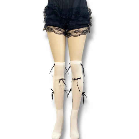 White knee high socks with bold black satin bow ribbons, balletcore legwear for Y2K and festival fashion.

