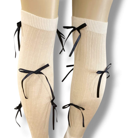 White knee high socks with bold black satin bow ribbons, balletcore legwear for Y2K and festival fashion.
