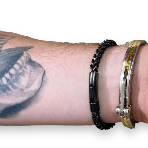 Men's Black Metal Rope Moto Bangle worn on a tattooed wrist, showcasing its twisted rope design and polished finish.