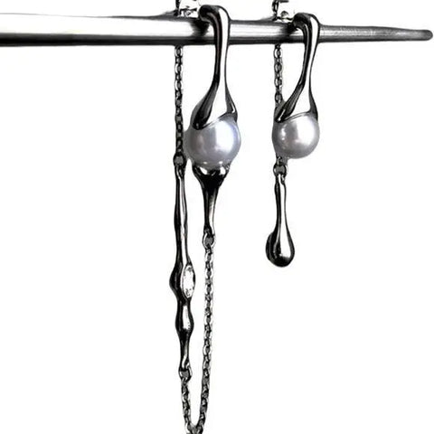 Silver asymmetrical pearl drop earrings with silver curb chains, simulated white pearls, and crystal accents, modern gothic and Y2K fashion jewelry.