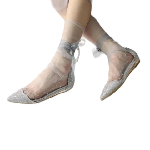 Model wearing sheer ankle socks with long pearl-accented ribbon ties in gray styled ballet flats or coquette or punk fashion