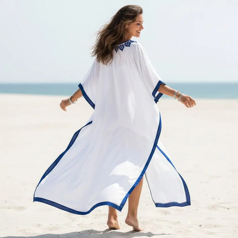 White Blue Embroidered Resort Kaftan flowing on the beach with blue embroidery accent.