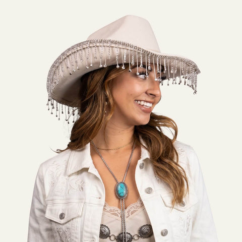 woman wearings with festival attire Sparkling Fringe White Cowboy Hat with rhinestone tassel trim, silver studded band, wide brim, and chin strap