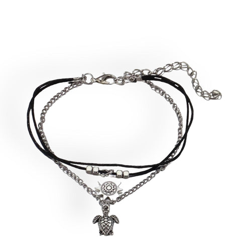 Close-up of silver turtle and sun charms on boho anklet
