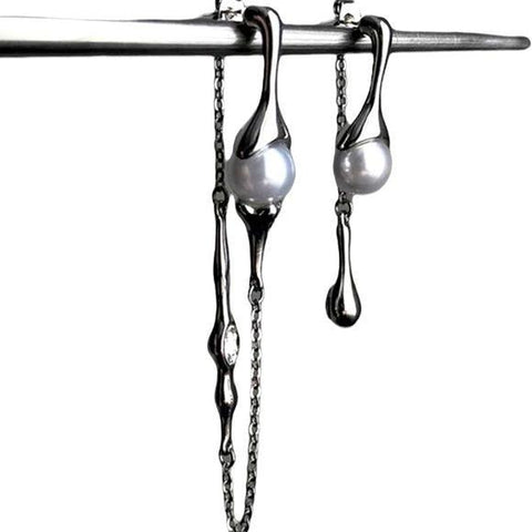Silver asymmetrical pearl drop earrings with silver curb chains, simulated white pearls, and crystal accents, modern gothic and Y2K fashion jewelry.